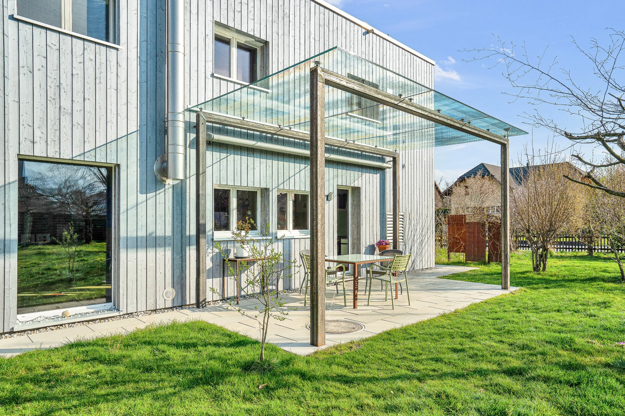 Pergola bündig an die Fassade eines Einfamilienhaus aus Metallkontruktion und einem Dach aus Glas