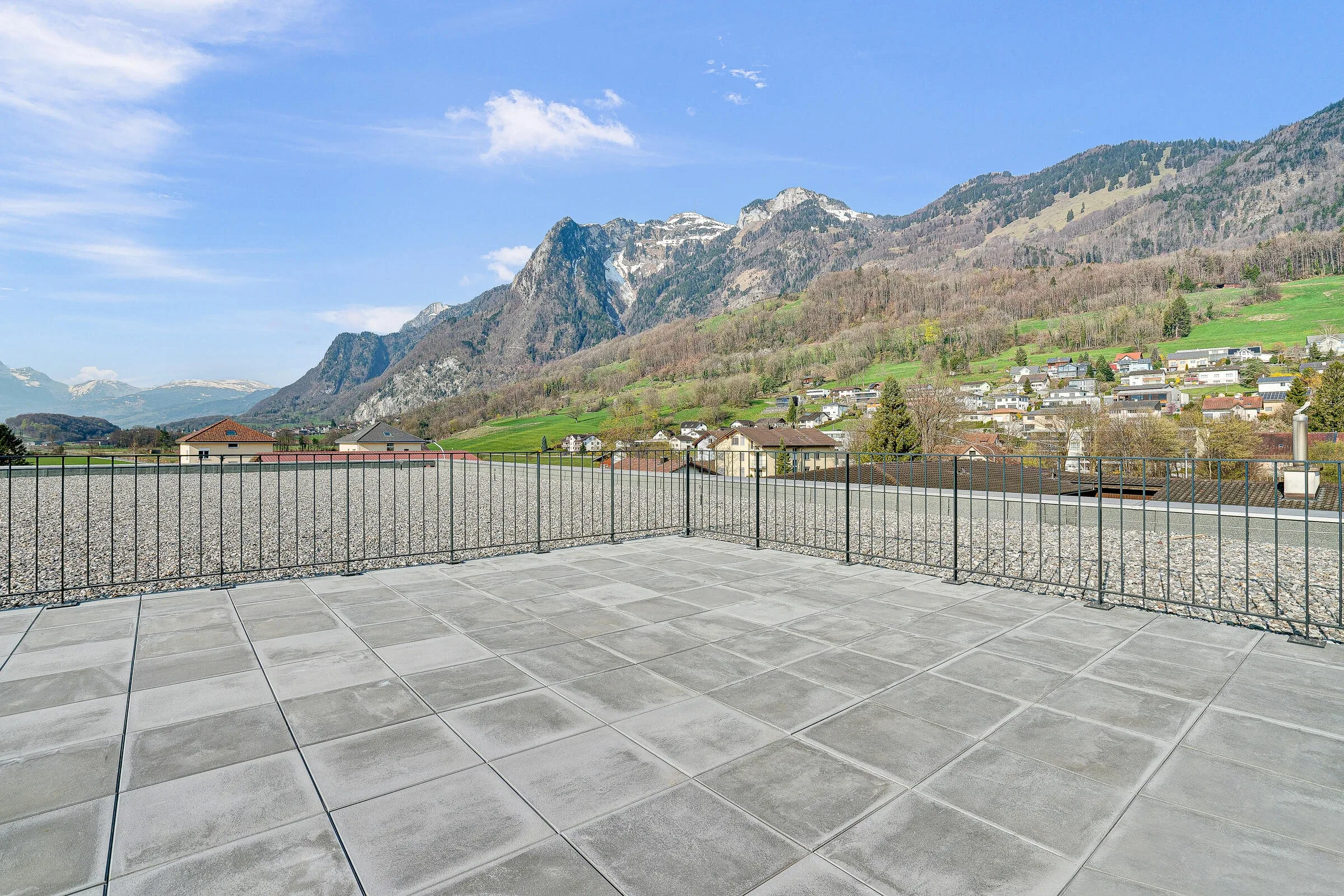 Dachterrasse mit Betonpflaster und minimalistischem Metallgelaender