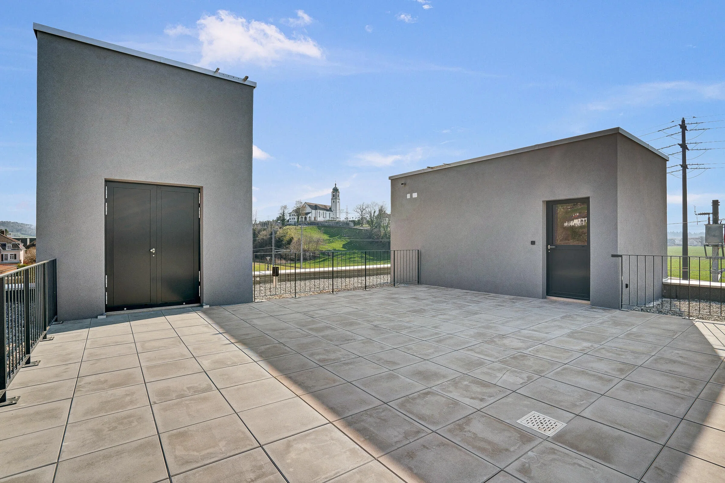Dachterrasse mit Metallgitter-Bruestung, Betontuerrahmen und Bergpanorama