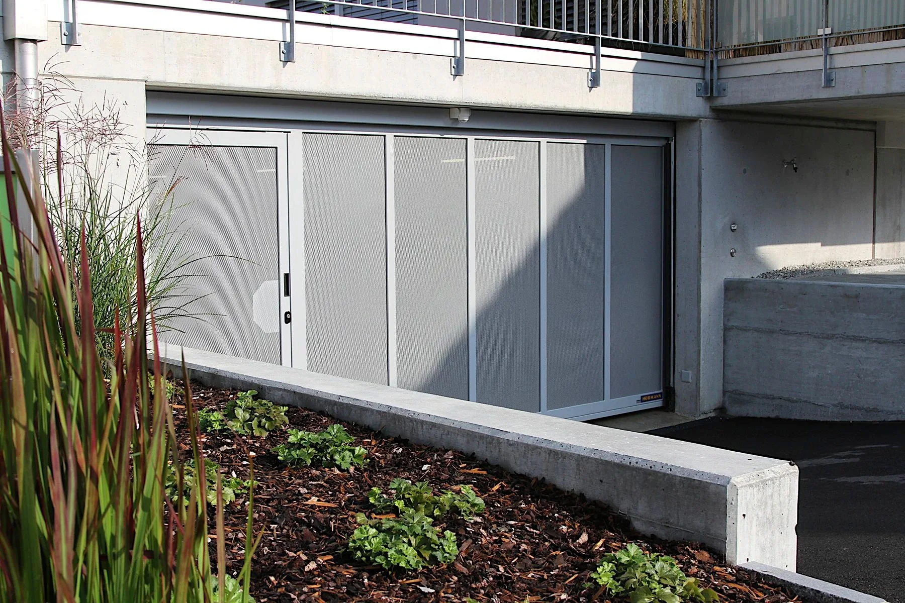 Begrünte Einfahrt mit einem Sammelgaragentor