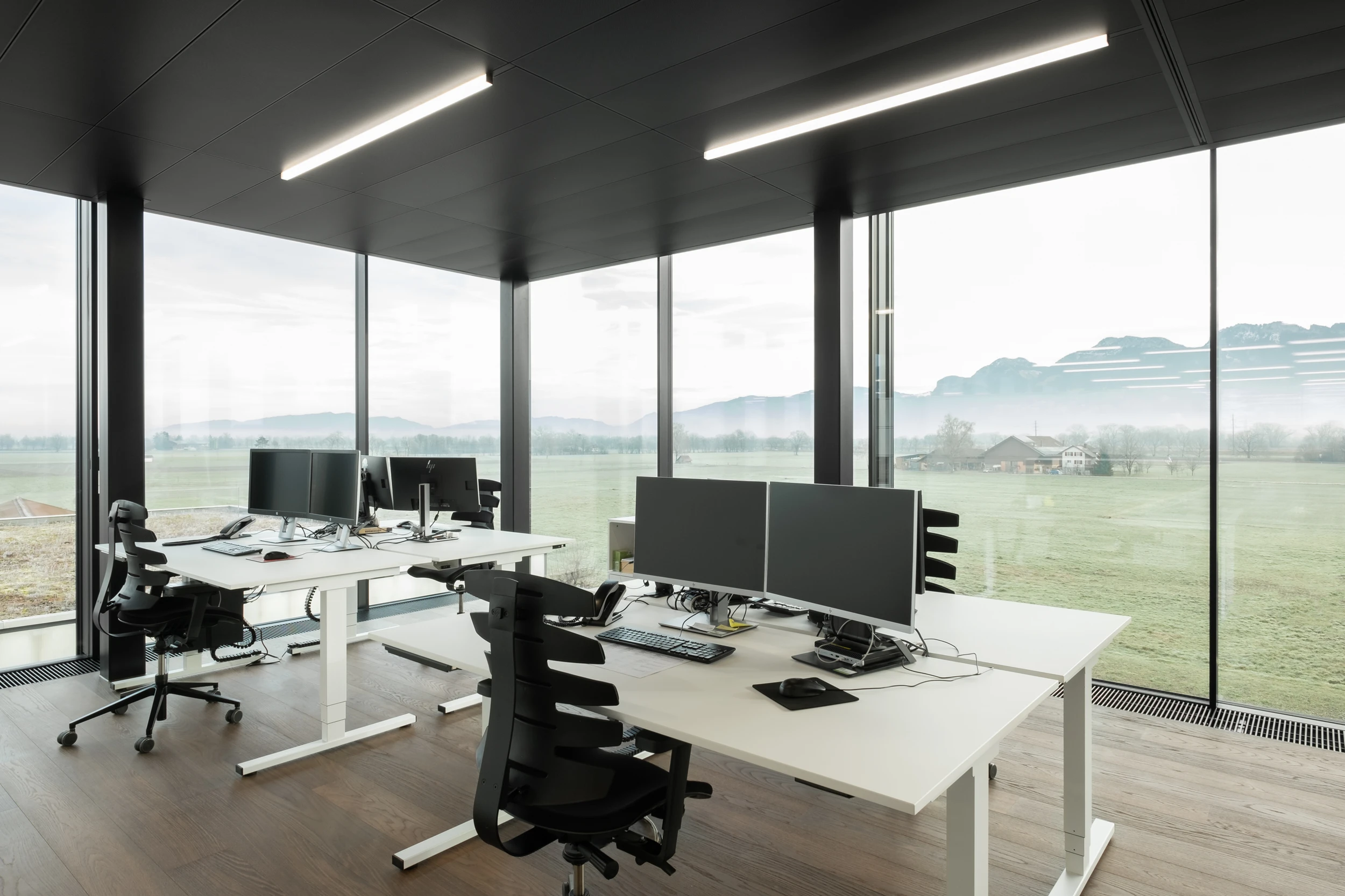 Büroräulichkeiten mit zwei Arbeitsplätzen und Sky-Frame Verglasung im Hintergrund