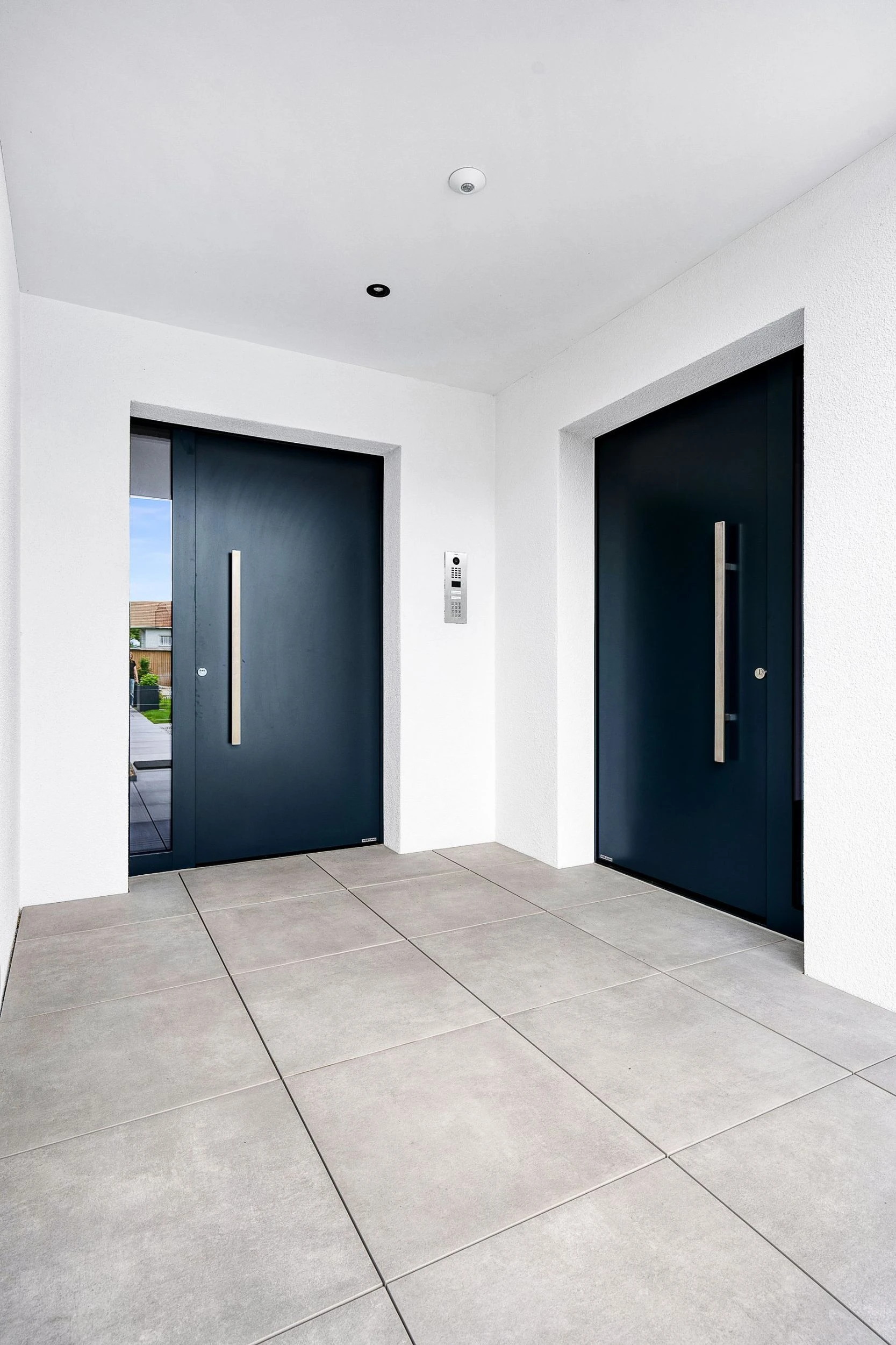 Einladender Blick in den Eingangsbereich zweier Wohneinheiten mit aufeinander abgestimmten Haustüren.