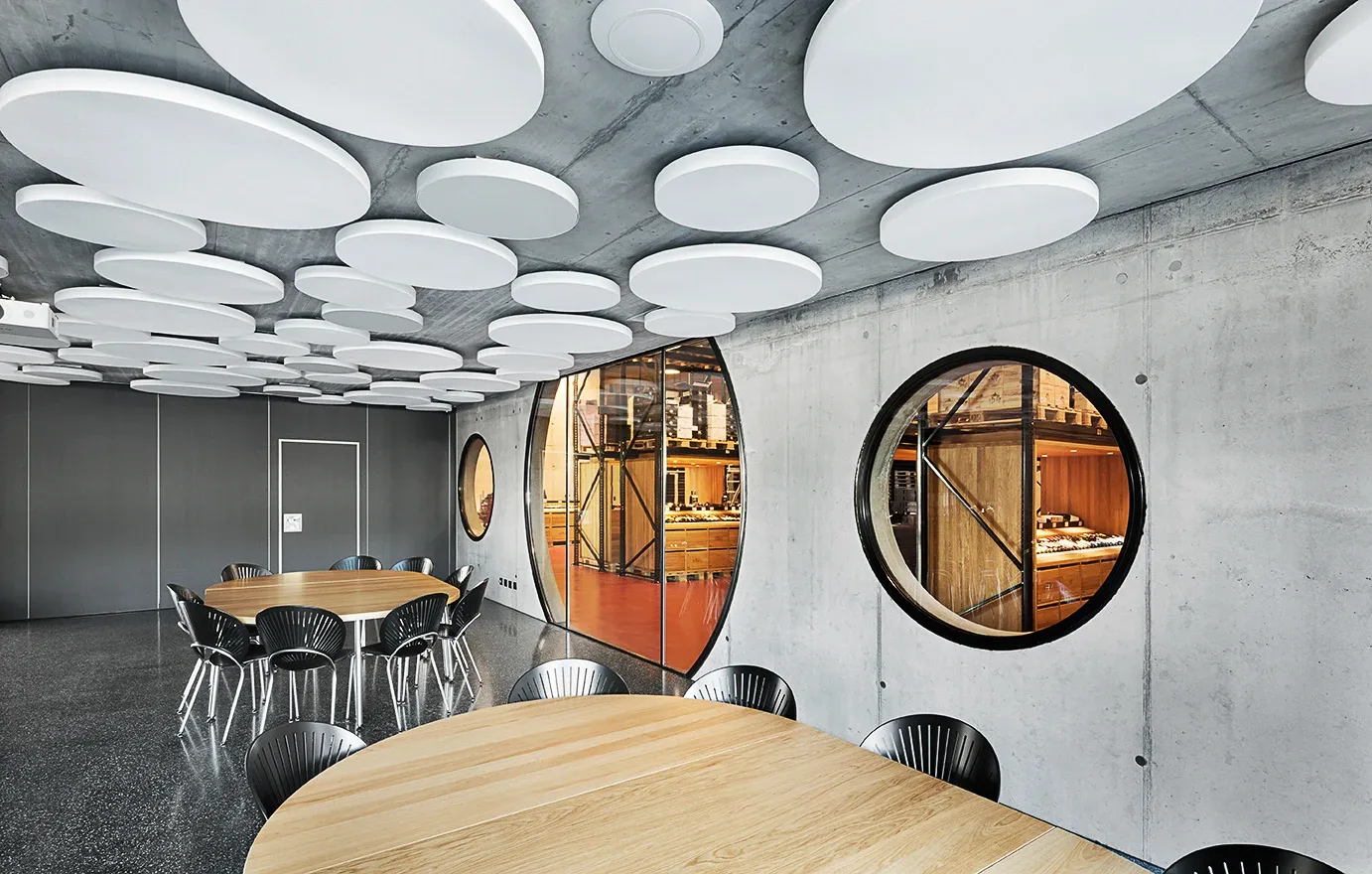 Eventraum mit runden Brandschutzverglasungen in Sichtbetonwaenden