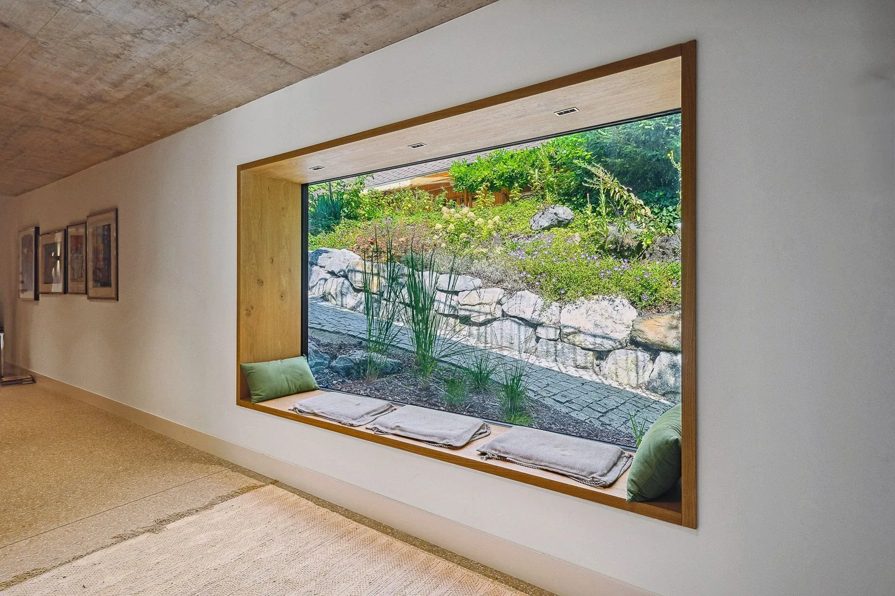Femster als Fixverglasung mit Sitzbank aus Holz mit einladenden Sitzkissen und Blick in den Garten