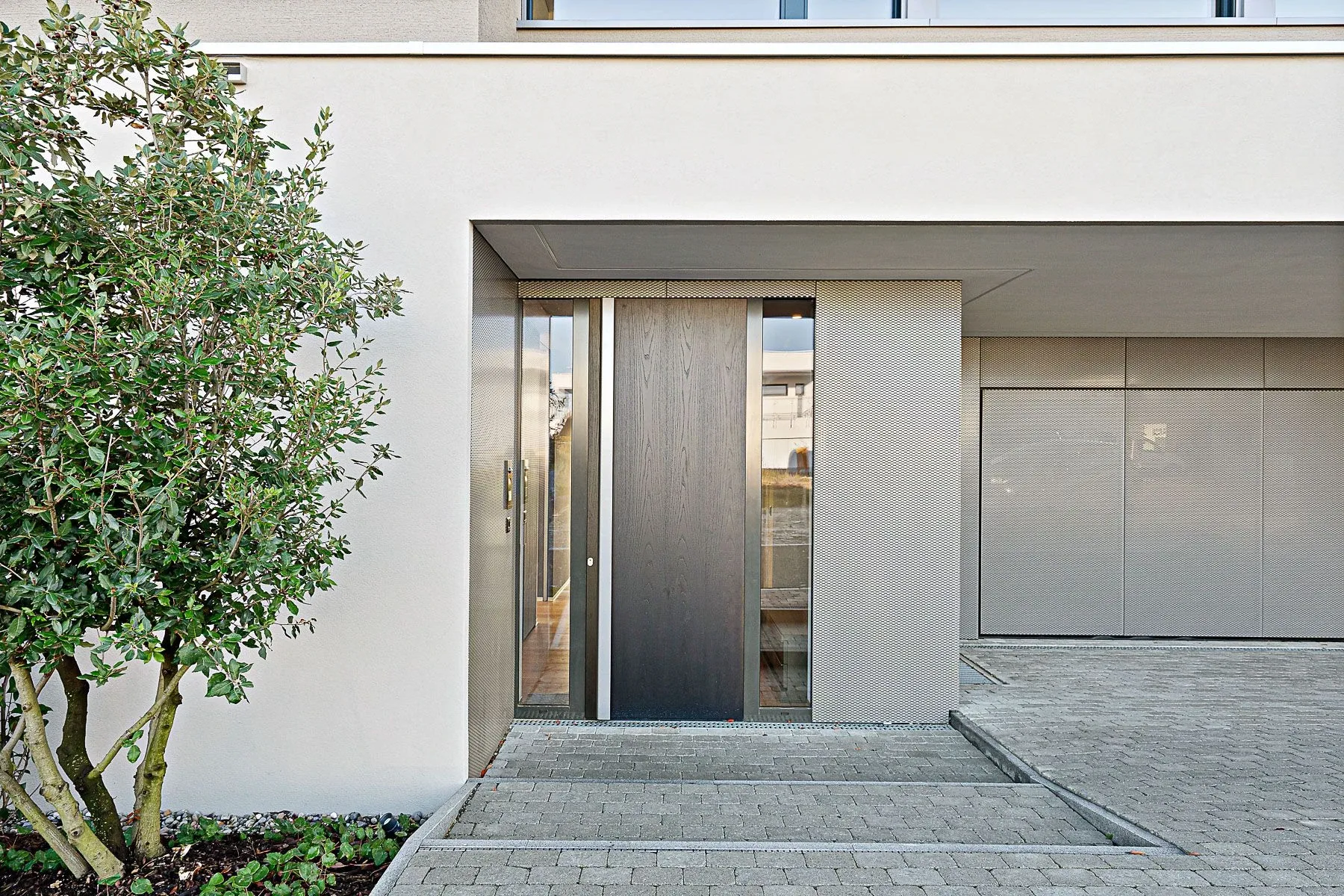 Holzbeplankte Schüco-Haustüre aus Aluminium mit beidseitig, verglasten Seitenteilen und eine Chromstahlstossstange, einwärts öffnend