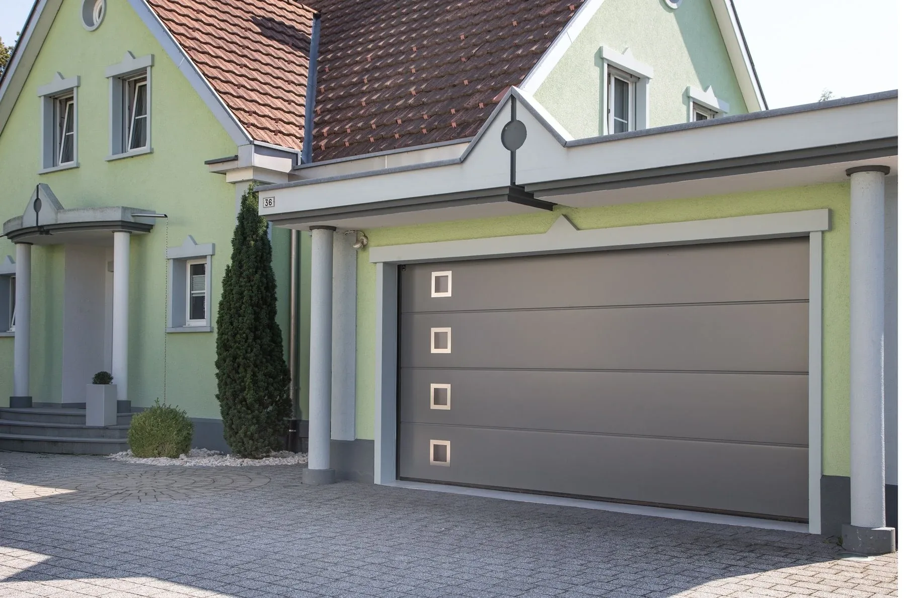 Klassisches Sektionaltor seitlich mit quadratischen satinierten Fenstern, passend zur Haustäre