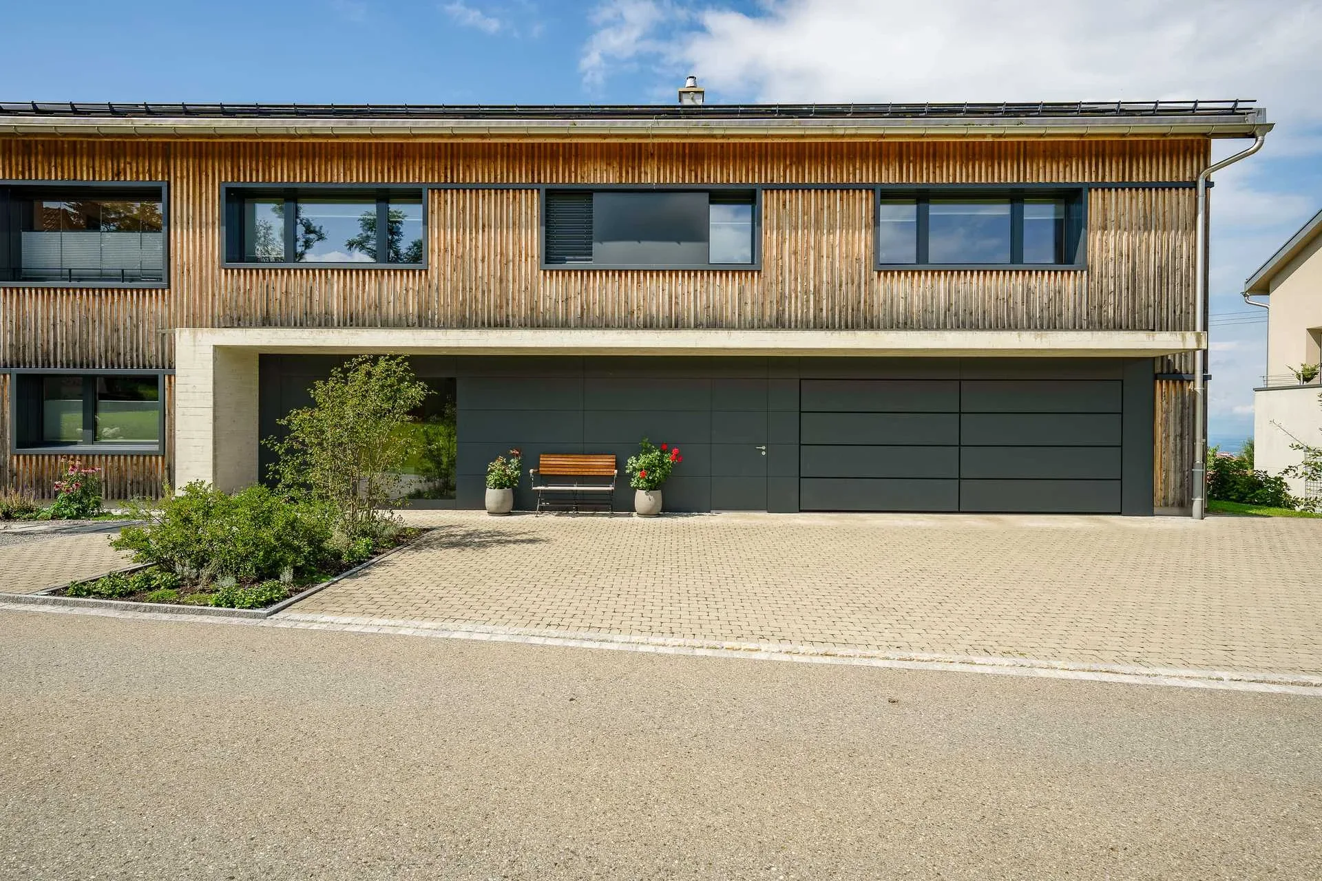 Einfamilienhaus im Appenzellerhaus mit Holzfassade, Sektionaltor und roter Sitzbank