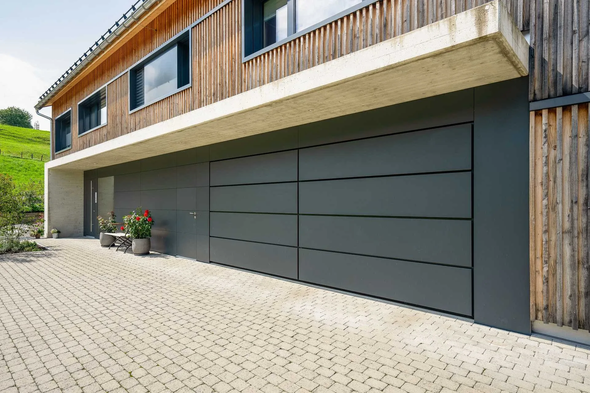 Nahaufnahme Haupthaus-Garagentor mit Sichtbeton-Sturz und Holzfassade darueber