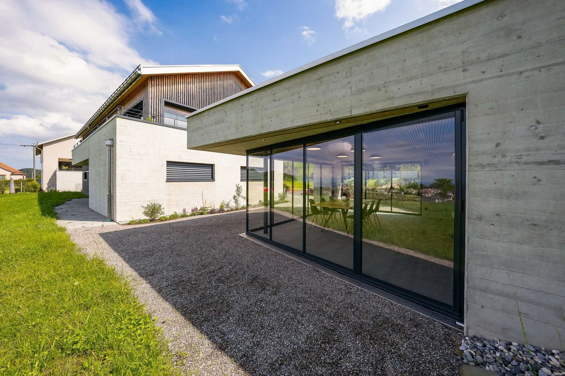 Pavillon mit Glasfront neben Haupthaus, Kiesweg im Vordergrund