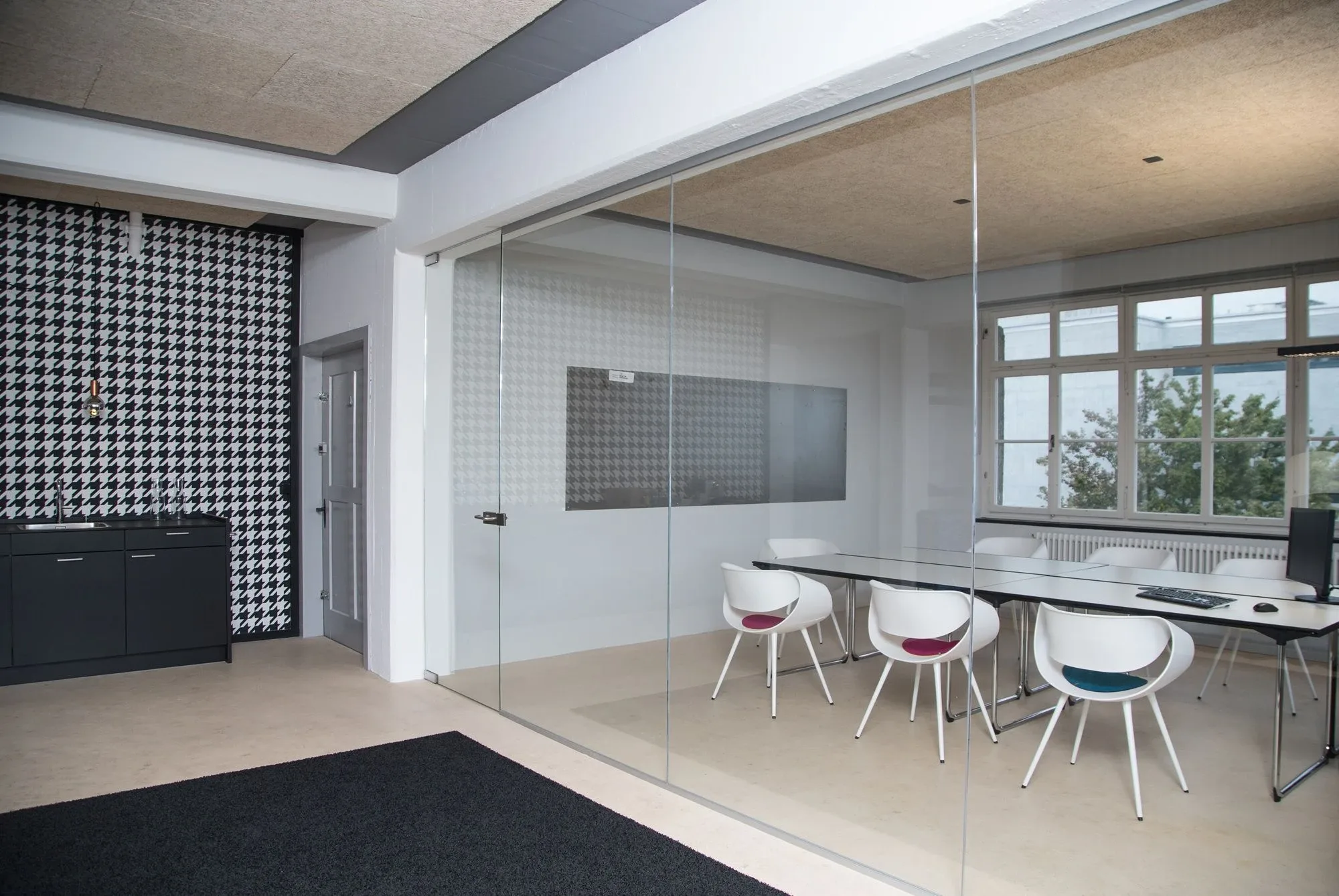 Sicht auf einen Innenverglasung welche ein Sitzungszimmer transparent schliesst, mit Flügeltüre