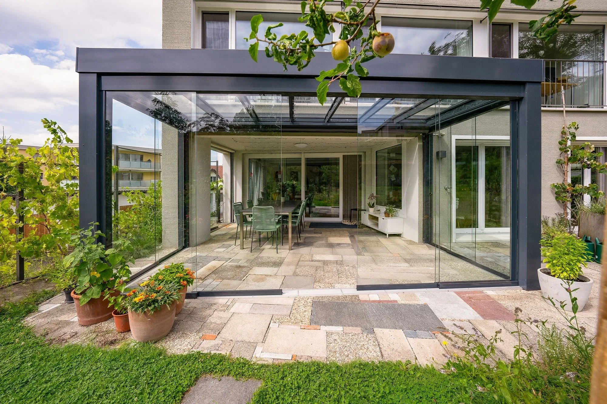 Sitzplatzverglasung mit Glasdach Acubis direkt ans Haus angesetzt mit dreiseitiger Terrassenverglasung mit Schiebegläsern
