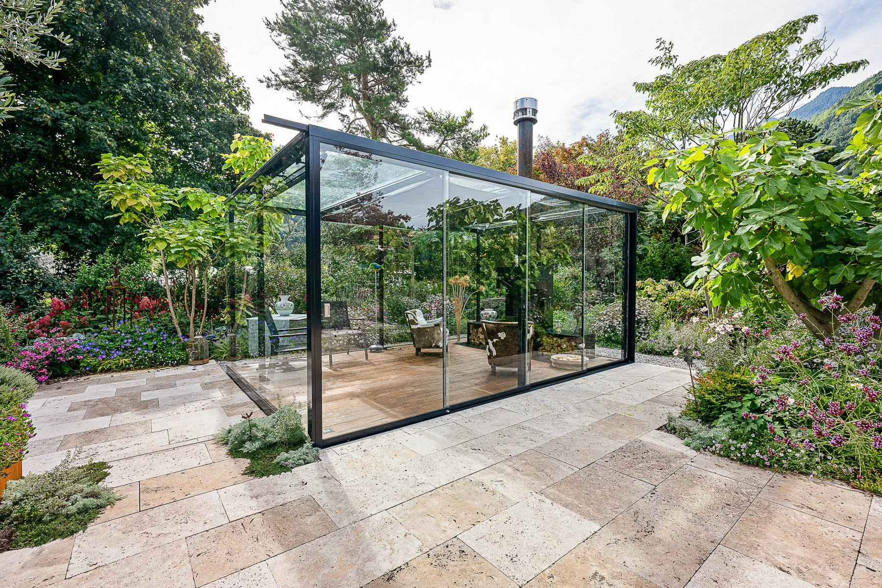Blick von aussen durch die Glasfront auf Sessel und Holzlager in der Lounge